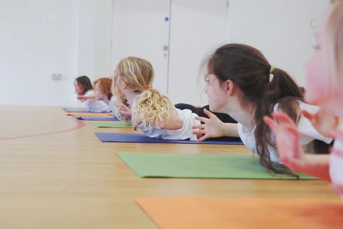 Pupils following a yoga class in a school hall