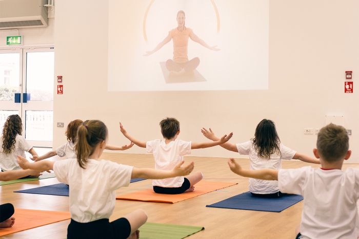 Pupils following a Well Ed yoga video in school